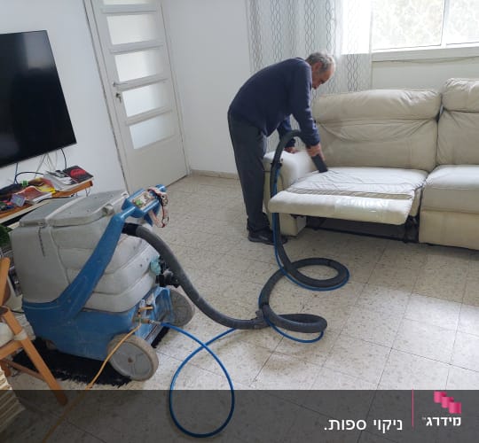 אדם מנקה ספה עם מכונת ניקוי מקצועית